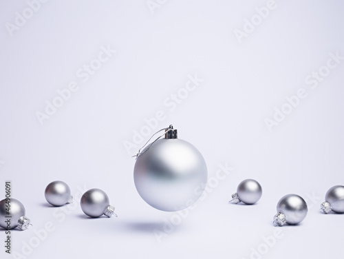 Creative Christmas layout made with flying and levitating bauble ornament with small silver balls on bright white background. Minimal Xmas or New Year celebration concept. Winter festive composition.