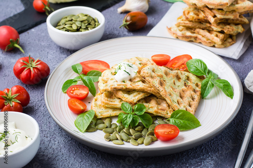 Appetizing zucchini waffles, tomatoes and pumpkin seeds on a plate on the table. Vegetable diet vegetarian food