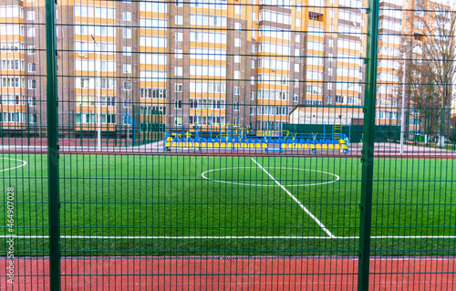 Football field with artificial lawn. Stadium and sports grounds near  near the apartment building.Central circle of stadium. The football field fenced with a green iron lattice