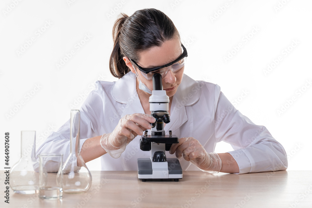lab technician looks into the eyepiece of a microscope, a young female doctor lab technician looks into the eyepiece of a microscope, a young female doctor