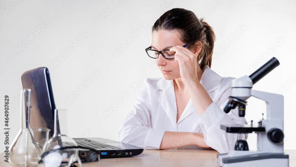 young woman, a laboratory assistant or a researcher is working at a laptop in the laboratory