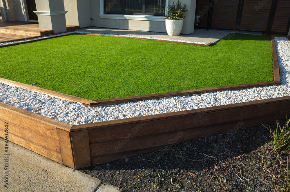 Artificial grass lawn turf with wooden edging in the front yard of a modern Australian home or residential house. - obrazy, fototapety, plakaty 
