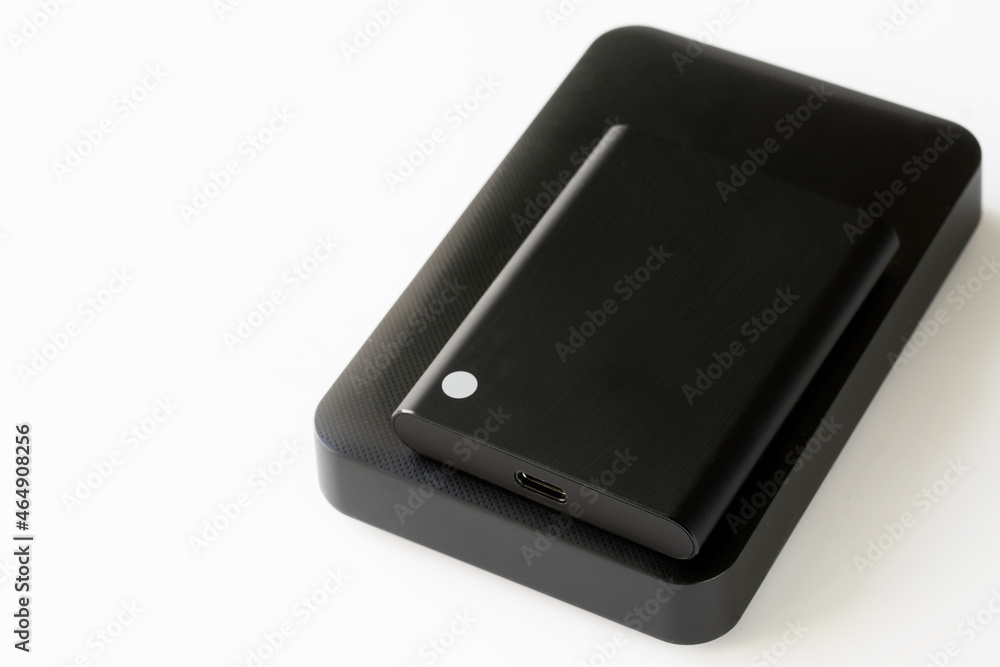 Comparison of sizes of external SSD and external 2.5-inch HDD. Computer digital peripherals. Data storage on external drives. Free space for an inscription. Selective focusing. Comparison of sizes of external SSD and external 2.5-inch HDD. Computer digital peripherals. Data storage on external drives. Free space for an inscription. Selective focusing.