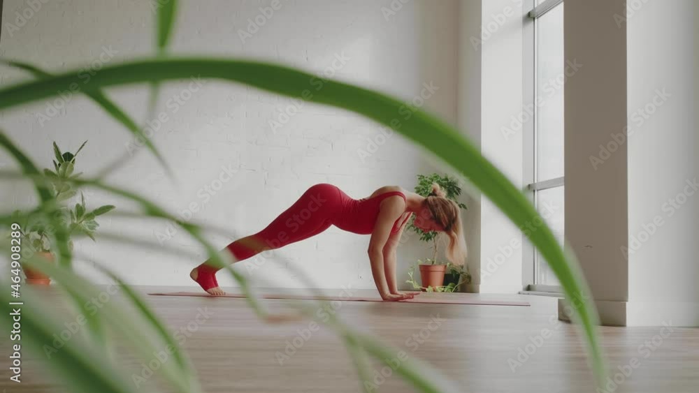 Beautiful yoga. Young woman in red sports uniform makes smooth body wave in white yoga studio with panoramic windows. Healthy lifestyle concept. High quality 4k footage Beautiful yoga. Young woman in red sports uniform makes smooth body wave in white yoga studio with panoramic windows. Healthy lifestyle concept. High quality 4k footage