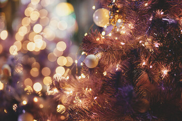 Stylish modern purple christmas tree on background of golden lights illumination bokeh. Atmospheric magic time. Christmas festive decor for winter holidays, copy space. Merry Christmas!