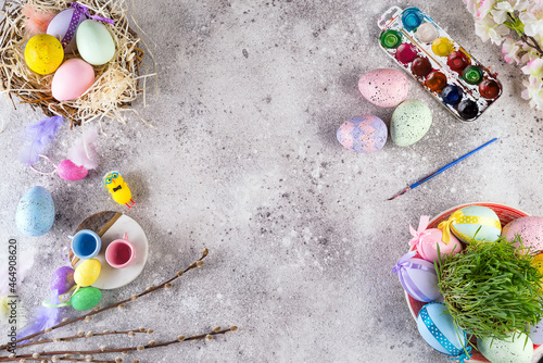 Easter eggs in a nest of grass, homemade glazed cookies and paints for painting eggs and grass as attributes of the preparation of the Easter holiday on a stone background, flat lay