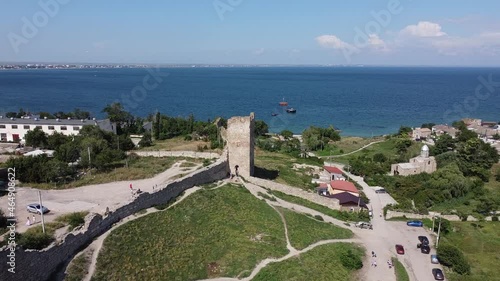 Scenic aerial view of the Tower of ancient ruined Genoese fortress Kaffa against blue sky and dark blue sea. Aerial static drone shot.