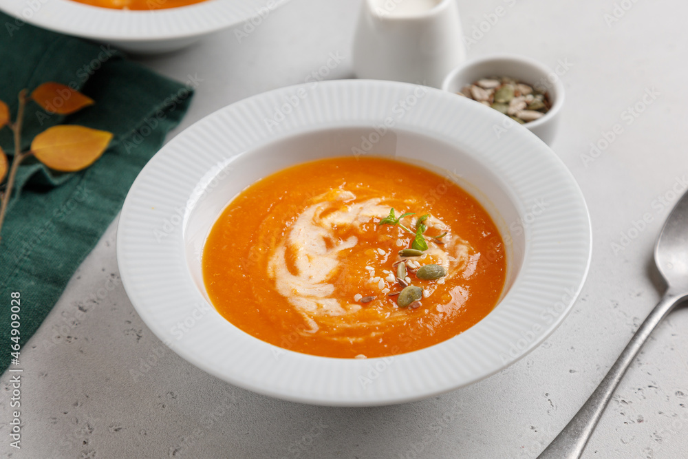 pumpkin soup with seeds and cream in a white plate on a gray table pumpkin soup with seeds and cream in a white plate on a gray table
