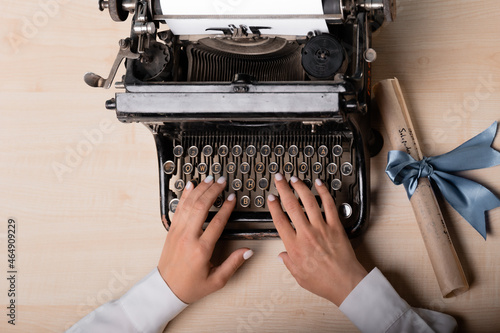 young woman author at a typewriter, writes a text. Retro vintage typewriter close-up, photo