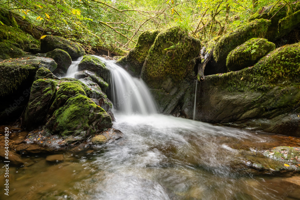 Long exposure of a waterfall on the Hoar Oak Water river flowing through the woods at Watersmeet in Exmoor National Park