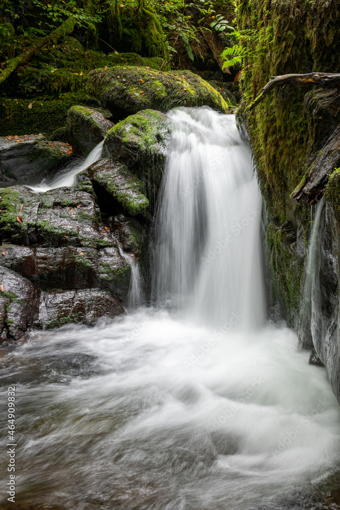 Long exposure of a waterfall on the Hoar Oak Water river flowing through the woods at Watersmeet in Exmoor National Park