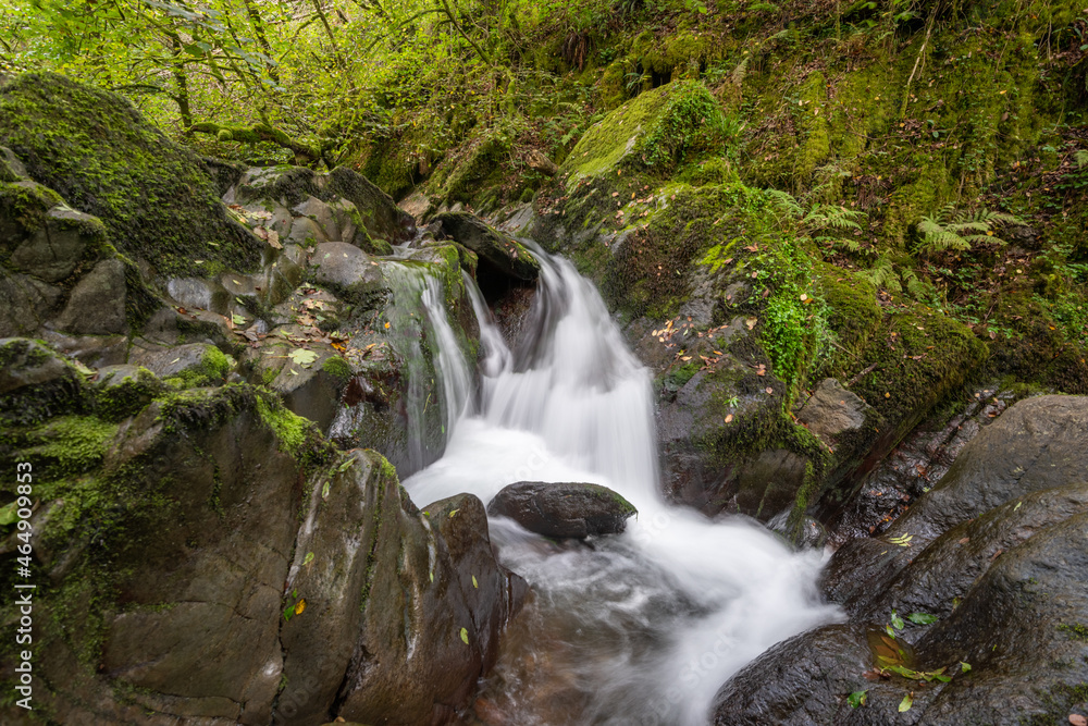 Obraz premium Long exposure of a waterfall on the Hoar Oak Water river at Watersmeet in Exmoor National Park