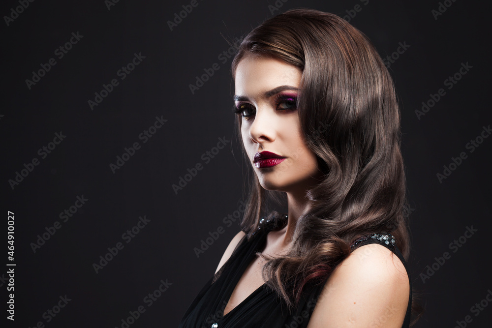 Naklejka premium Gorgeous young brunette in a chic evening look. Scarlet lips and eye shadow, wave hair styling