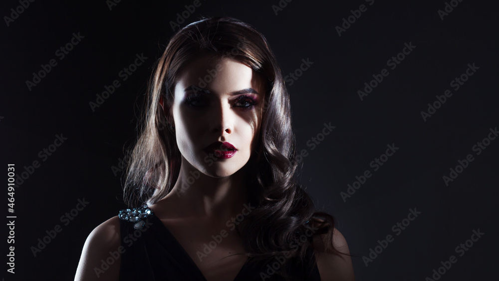 Fototapeta premium A mysterious gorgeous pale lady with dark hair and scarlet lipstick in the shade.