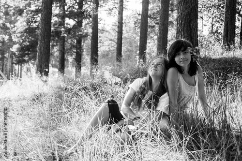 Two teen girl sitting on the grass in the summer park. Black and white photo.