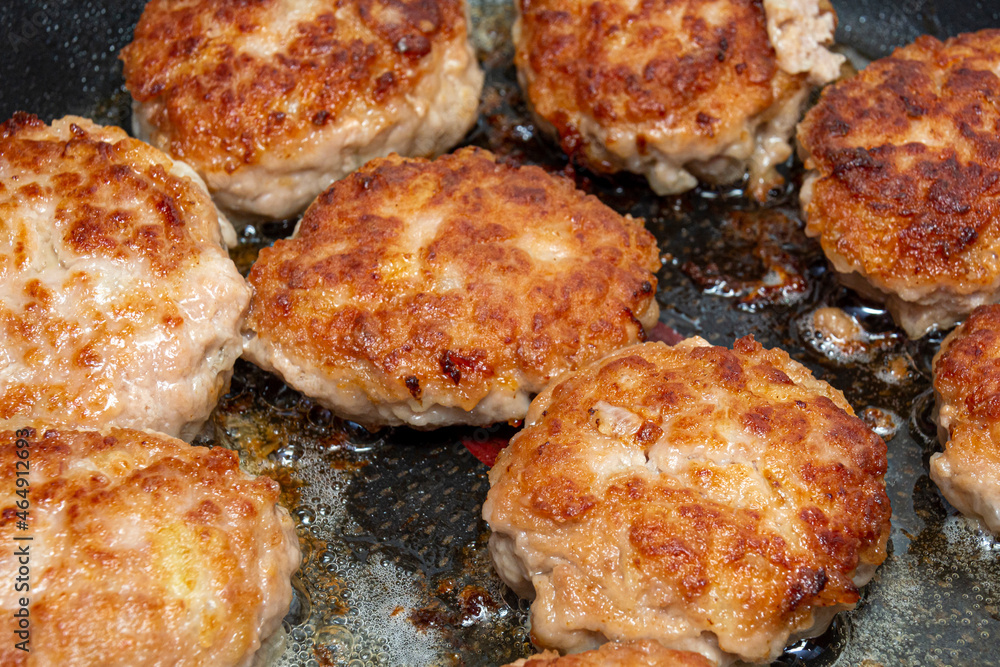 Minced meat cutlets are fried in a frying pan. Food background, close-up, top view.