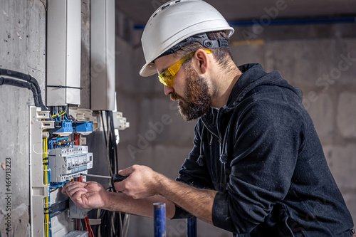 Schilderij op canvas A male electrician works in a switchboard with an electrical connecting cable