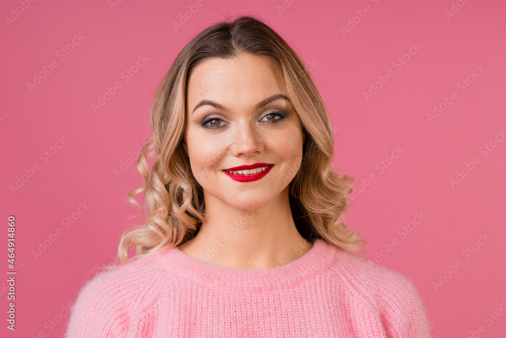 Fototapeta premium Young attractive woman in a warm pink sweater on a pink background,