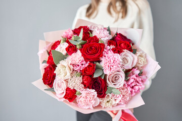 European floral shop. Red and pink Beautiful bouquet of mixed flowers in womans hands. the work of the florist at a flower shop. Delivery fresh cut flower.