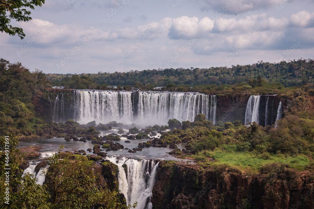 a waterfall in the middle of the forest with blue sky in the background.