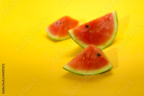 Close-up view of fresh ripe watermelon slice with defocus watermelon slices background isolated on orange background. Tropical fruits, healthy eating, and summer background concept.