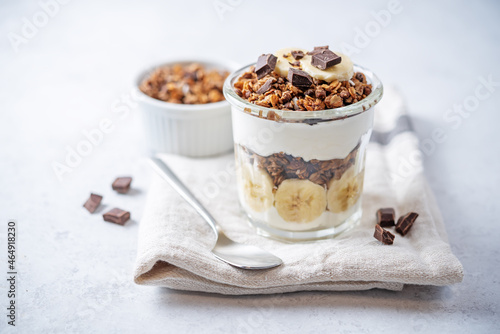 Chocolate and banana Greek yogurt granola parfait in a glass
