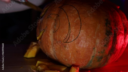 The girl carves a pumpkin for the holiday haluin on the pumpkin markup. red backlight. photo