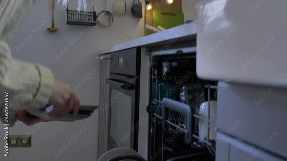 woman puts a plate in the dishwasher. Caring for the environment woman puts a plate in the dishwasher. Caring for the environment