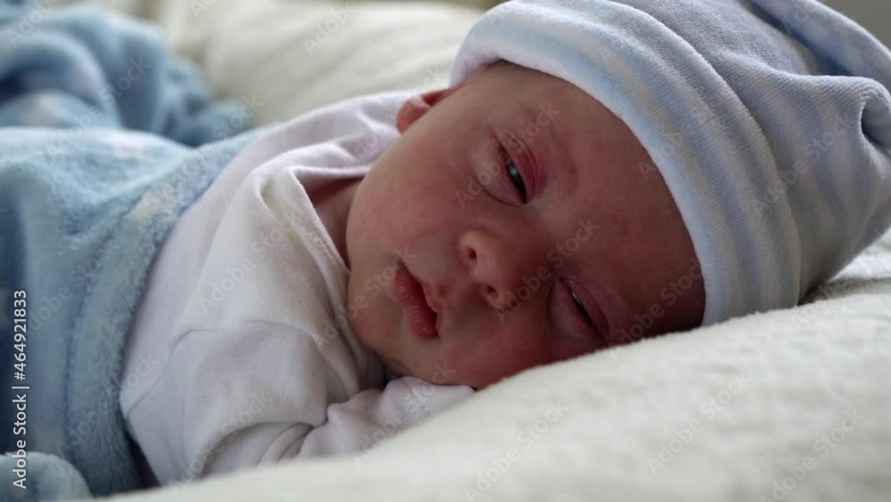 Close-up Newborn Baby Face Portrait Early Days Sleeping Sweetly On Tummy Blue White Background. Child At Start Minutes Of Life on Hat. Infants, Childbirth, First Moments Of Borning, Beginning Concept Close-up Newborn Baby Face Portrait Early Days Sleeping Sweetly On Tummy Blue White Background. Child At Start Minutes Of Life on Hat. Infants, Childbirth, First Moments Of Borning, Beginning Concept