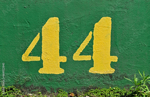 Number 44 painted in yellow on a green wall