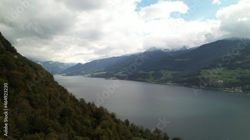 Establish fjord lake Panorama with steep mountain cliff, cloudy day, arial orbit