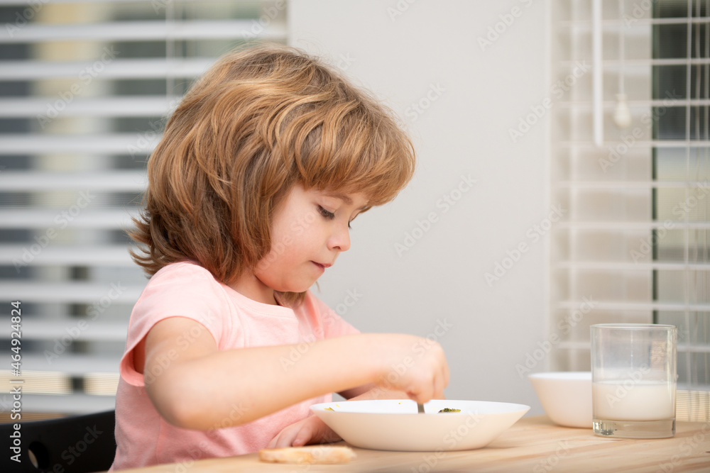 Caucasian toddler child boy eating healthy soup in the kitchen. Healthy nutrition for kids. Caucasian toddler child boy eating healthy soup in the kitchen. Healthy nutrition for kids.