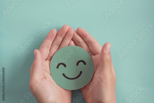 Hands holding green happy smile face, good feedback rating,positive customer review, experience, satisfaction survey ,assessment, child wellness,world mental health day, Compliment Day concept photo