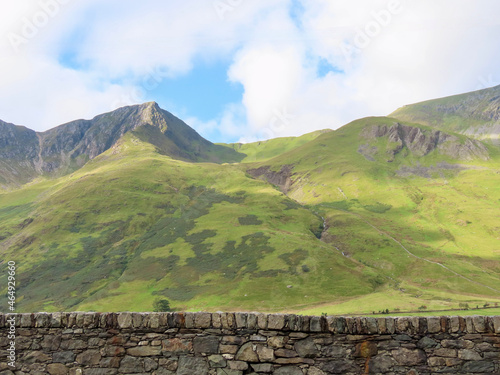 Mountain landscape of rocks and green gras in Snowdonia National Park, North Wales, with slate stone wall in foreground