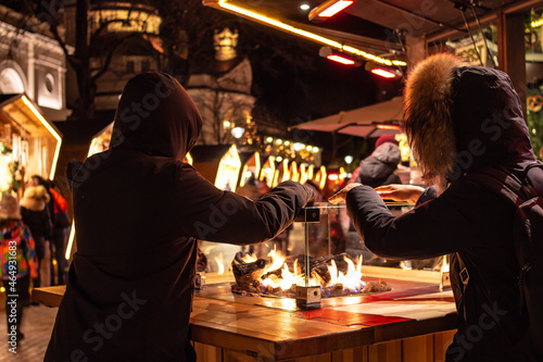 Kids holding their hands over fire place at traditional famous christmas market (christkindlmarkt) at Merano, South Tyrol / Italy