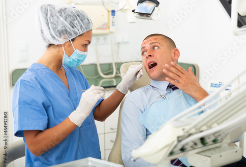 Unhappy male patient having a toothache in dental chair at modern dental clinic