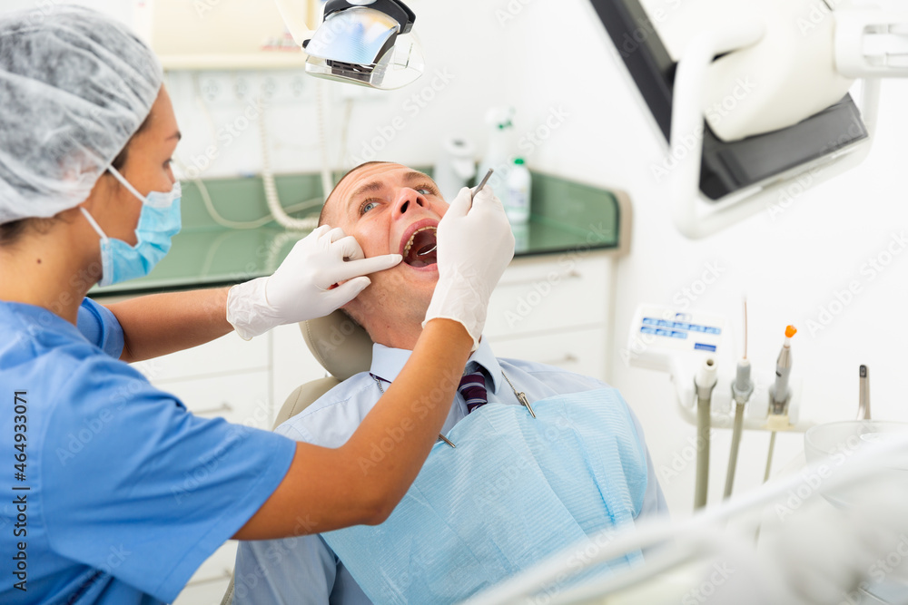 Female dentist examines the oral cavity of female patient. Dental treatment in a dental clinic