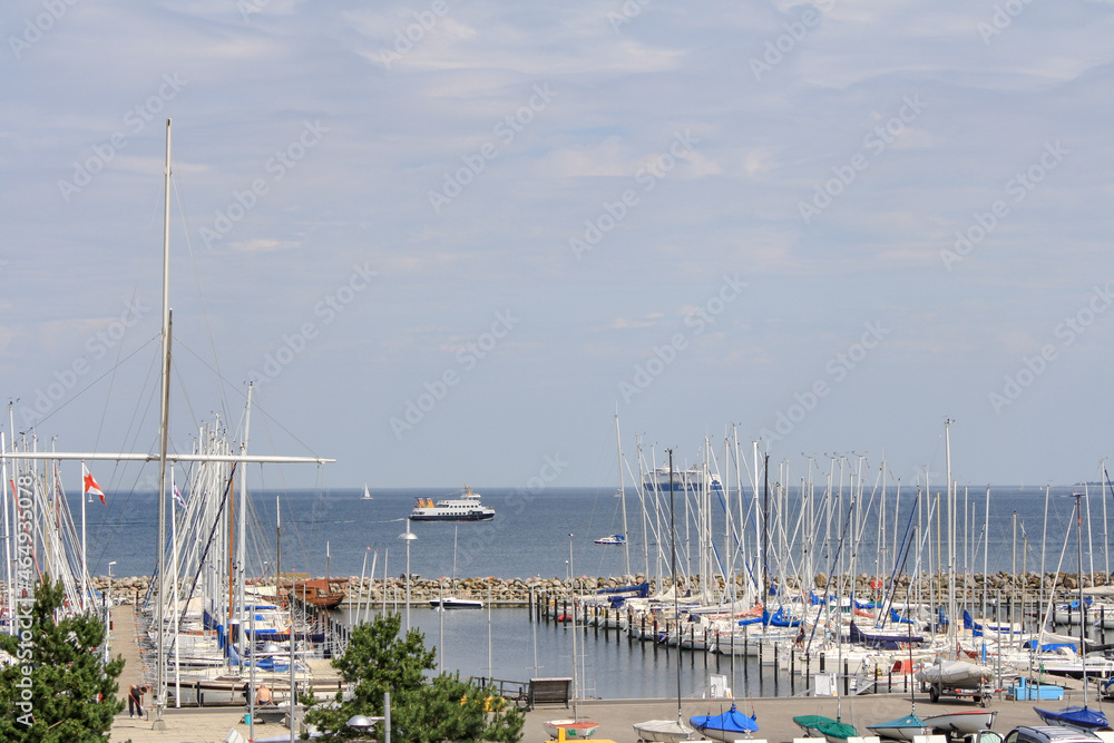 View sailboats docked at the pier viewed from University of Kiel Sailing Center in summer with clouds in blue sky background.