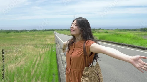 attractive female brushing her hair with hand is extending her arm and breathing in the fresh air in the countryside of King Kong Avenue on a breezy summer day. photo