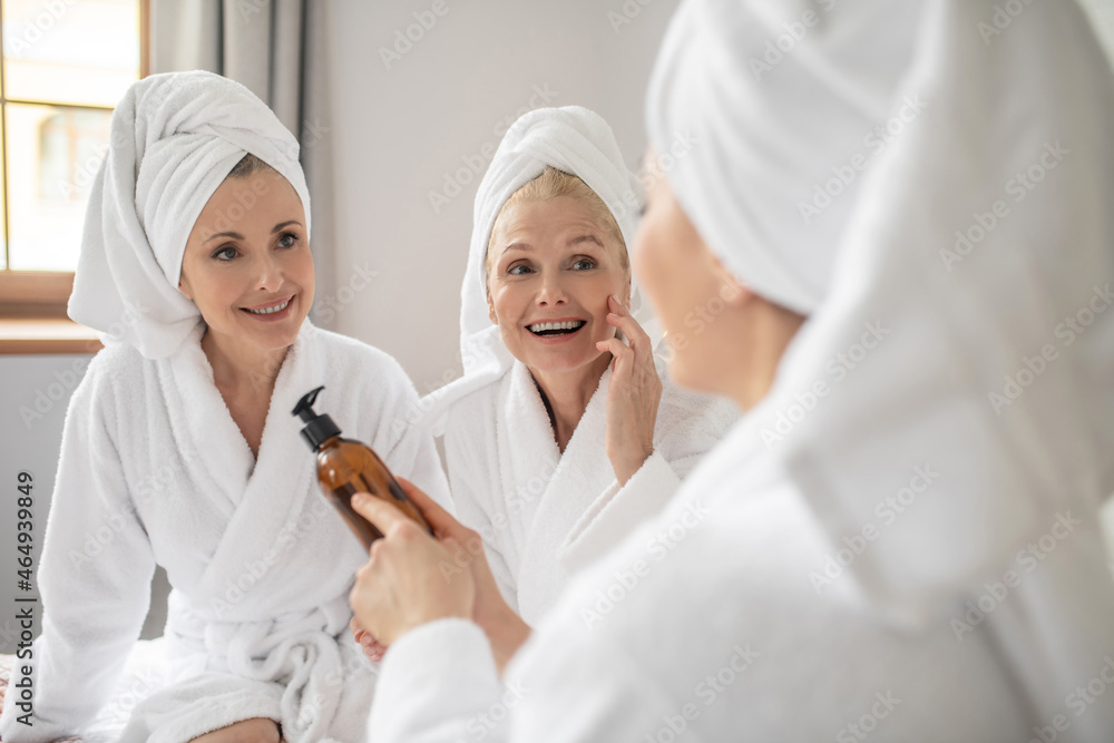 Three women studying composition of cosmetic product Three women studying composition of cosmetic product