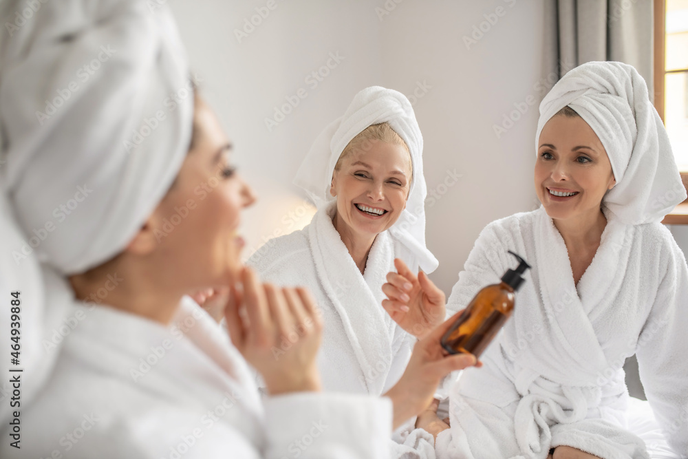 Obraz premium Three girlfriends with pleasure trying new cosmetic product