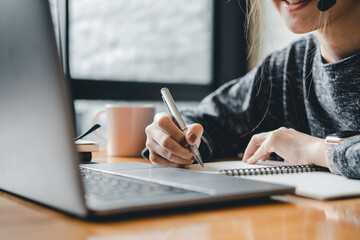 Close up photo of woman writing making list taking notes in notepad working or learning on laptop indoors- educational course or training, seminar, education online concept