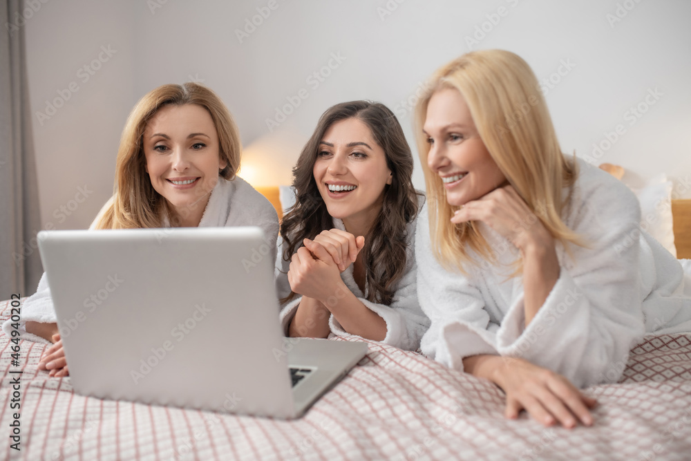 Middle aged women lying looking at laptop