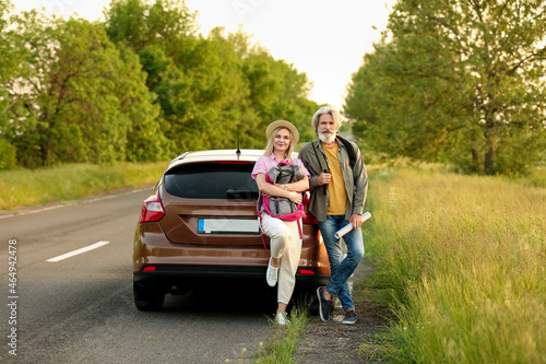 Happy mature couple with backpacks and map near car in countryside © Pixel-Shot