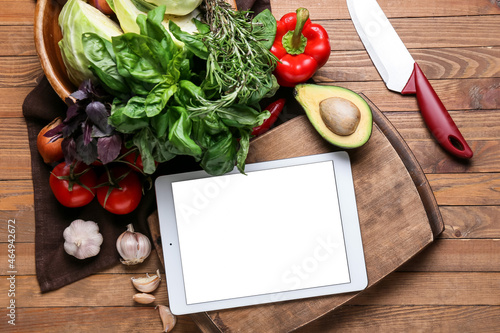 Digital recipe book, greens, vegetables and knife on wooden background