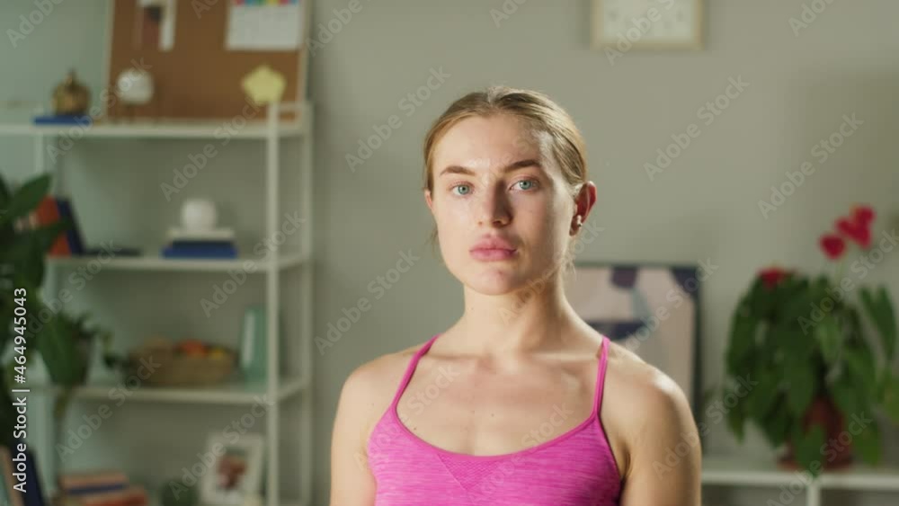 Sportswoman portrait. Young blonde woman looking in camera with serious look close-up. Fitness trainer standing in living room, home gym concept. Remote workouts during covid quarantine. Sportswoman portrait. Young blonde woman looking in camera with serious look close-up. Fitness trainer standing in living room, home gym concept. Remote workouts during covid quarantine.
