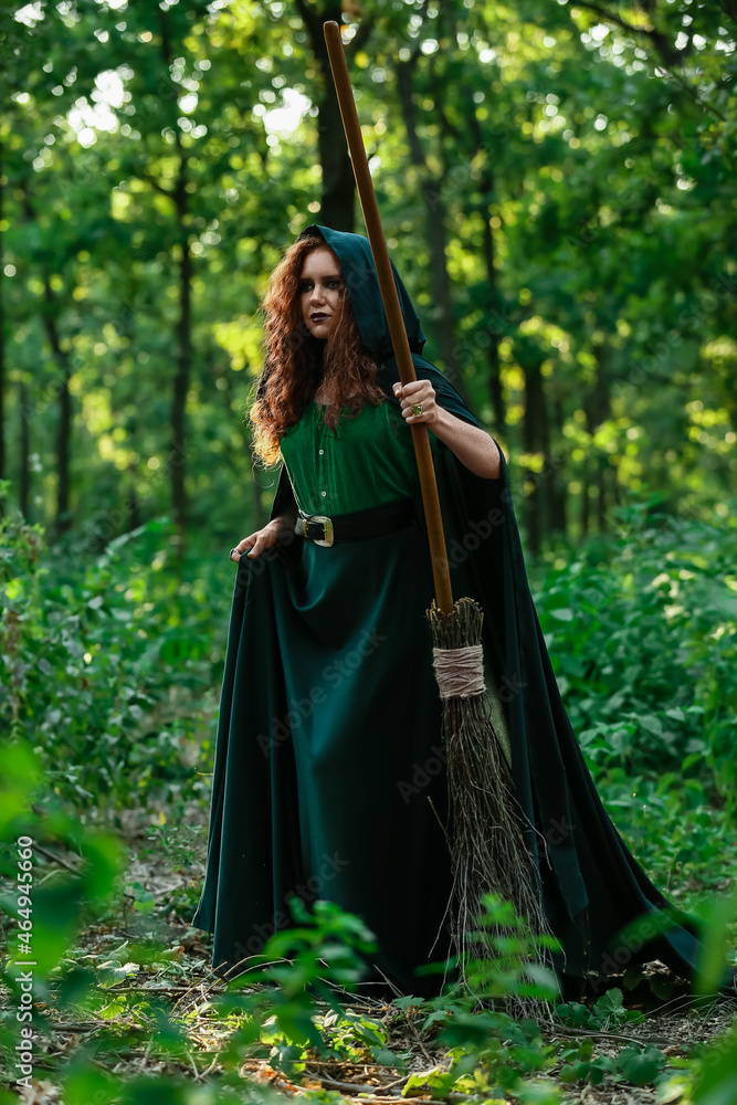 Young witch with broom in green forest Young witch with broom in green forest