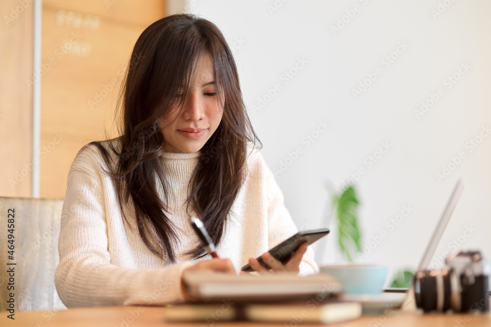 Beautiful college student writing on a memo notes, taking notes