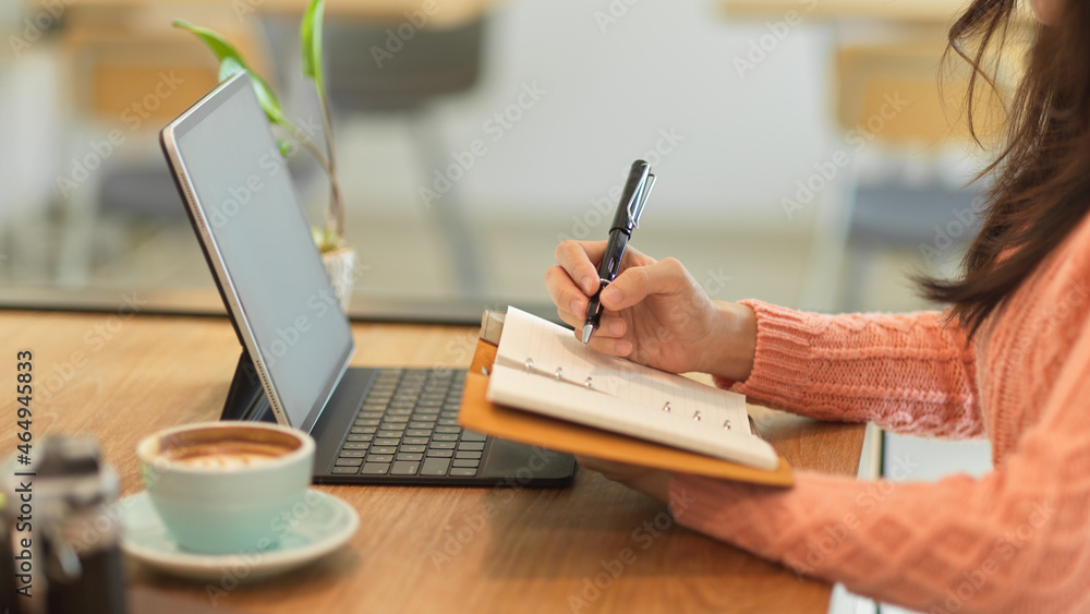 Fototapeta premium Female college student studying on her online class and lecturing on notebook.