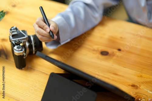 Close-up simple wooden worktable with camera, tablet computer